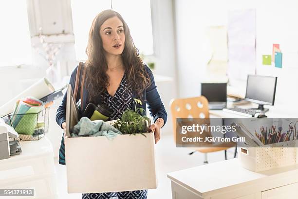 hispanic businesswoman carrying cardboard box in office - downsizing unemployment bildbanksfoton och bilder