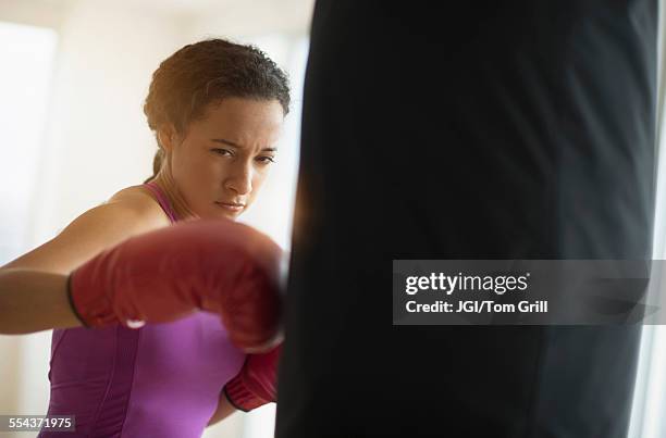 mixed race woman hitting punching bag in gym - mixed boxing bildbanksfoton och bilder