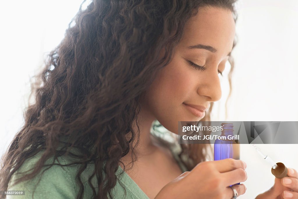 Close up of mixed race woman smelling aromatherapy oil