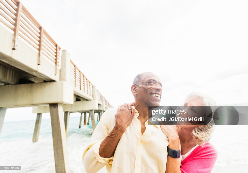 Older couple walking under boardwalk on beach