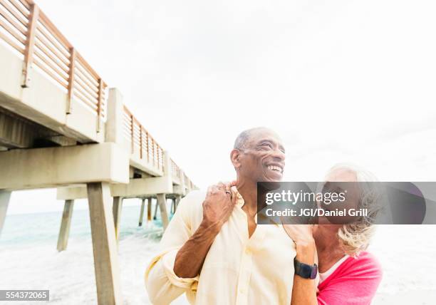 older couple walking under boardwalk on beach - jupiterimages stock pictures, royalty-free photos & images