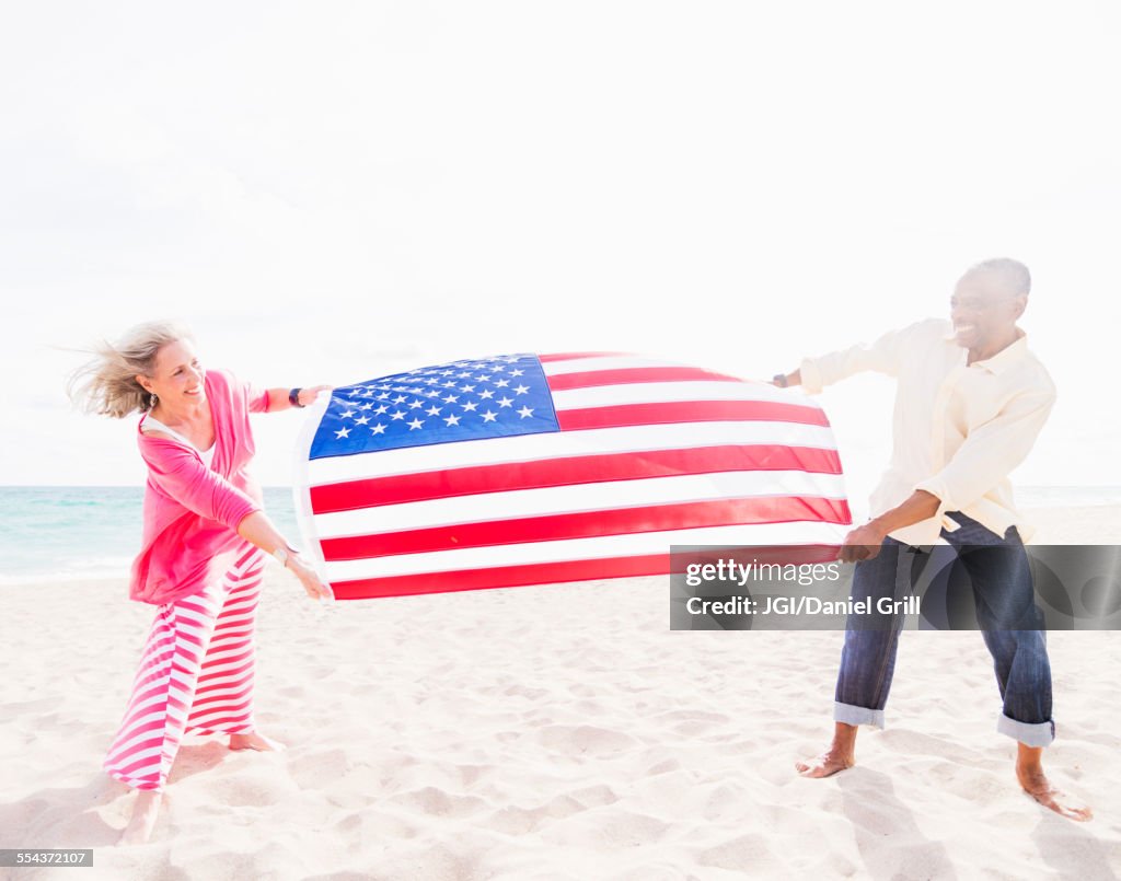 Older couple holding American flag on beach