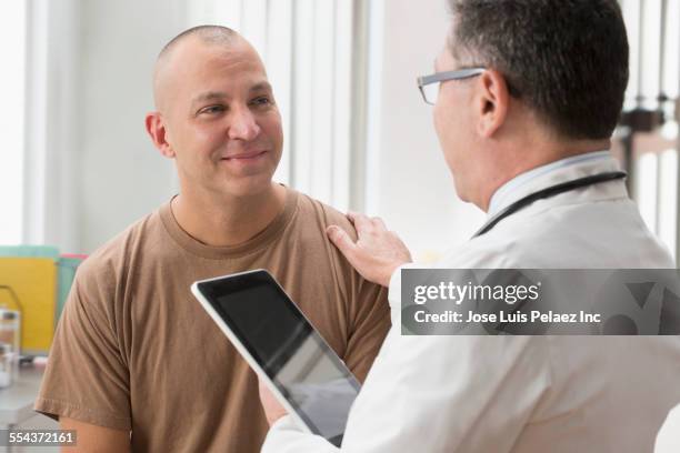 caucasian soldier and doctor talking in office - man touching shoulder stock-fotos und bilder