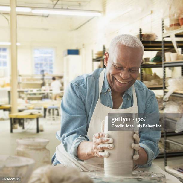 older black man forming pottery on wheel in studio - man pottery stock pictures, royalty-free photos & images