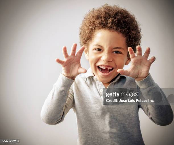 mixed race boy with curly hair and missing tooth growling - snarling stockfoto's en -beelden