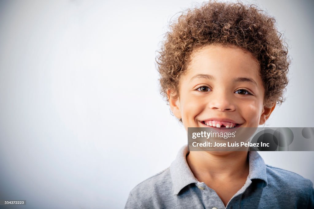 Mixed race boy with curly hair and missing tooth smiling