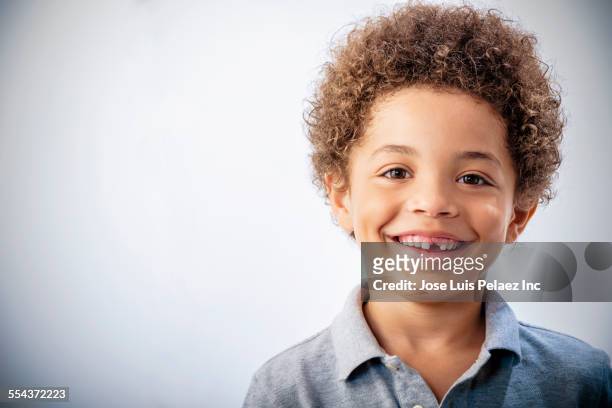 mixed race boy with curly hair and missing tooth smiling - multiracial person stock pictures, royalty-free photos & images