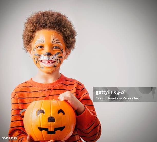 mixed race boy with tiger costume and halloween jack-o-lantern bucket - tierkostüm stock-fotos und bilder