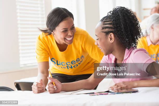 volunteer tutoring student in classroom - jamaicaanse etniciteit stockfoto's en -beelden