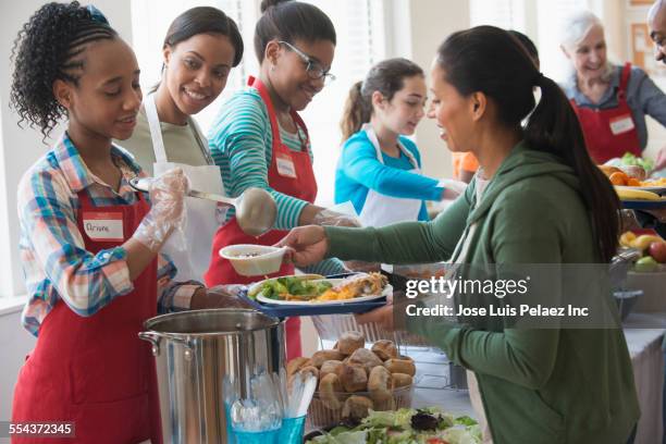 volunteers serving food at community kitchen - soppkök bildbanksfoton och bilder
