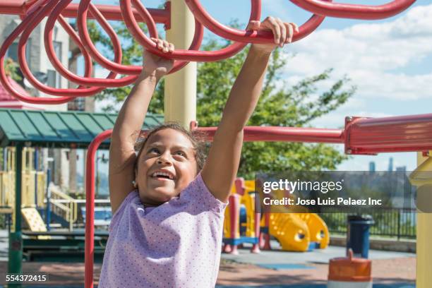 hispanic girl playing on monkey bars at playground - west new york new jersey stock pictures, royalty-free photos & images