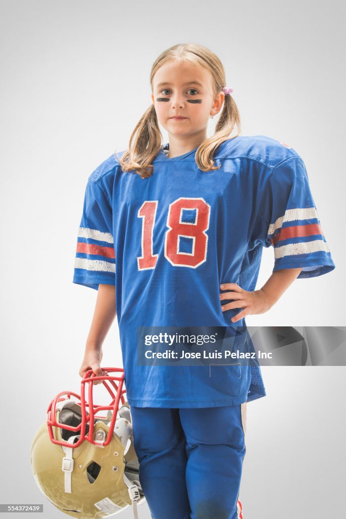 Caucasian girl wearing football jersey and helmet