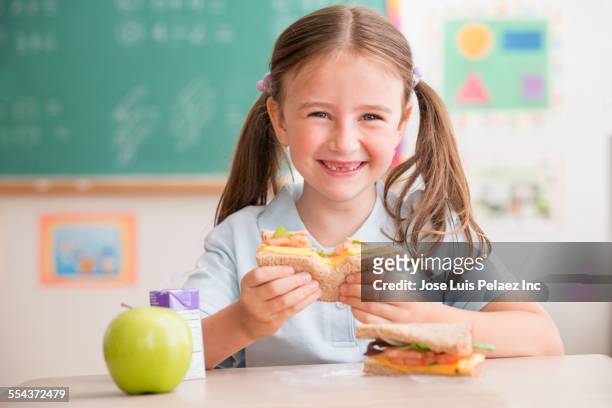 caucasian student eating lunch in classroom - school lunch stockfoto's en -beelden