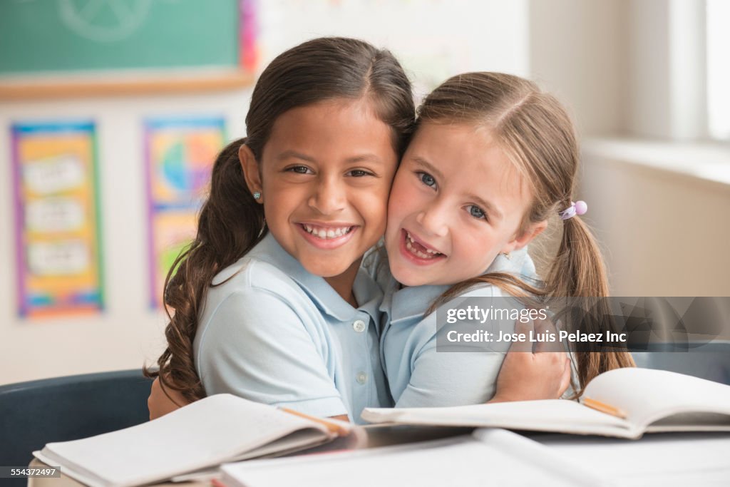 Smiling students hugging in classroom