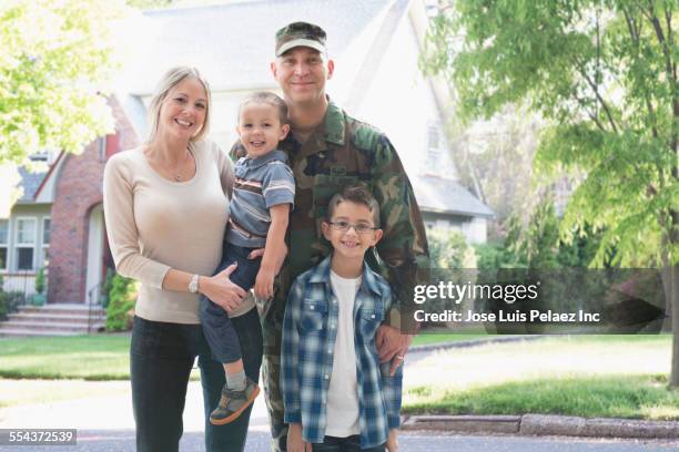 soldier and family smiling outside suburban house - armed forces military family stock pictures, royalty-free photos & images