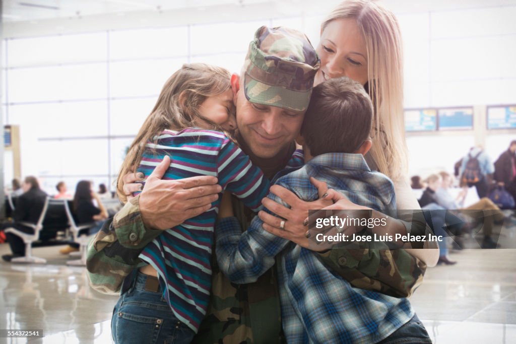 Caucasian returning soldier greeting family