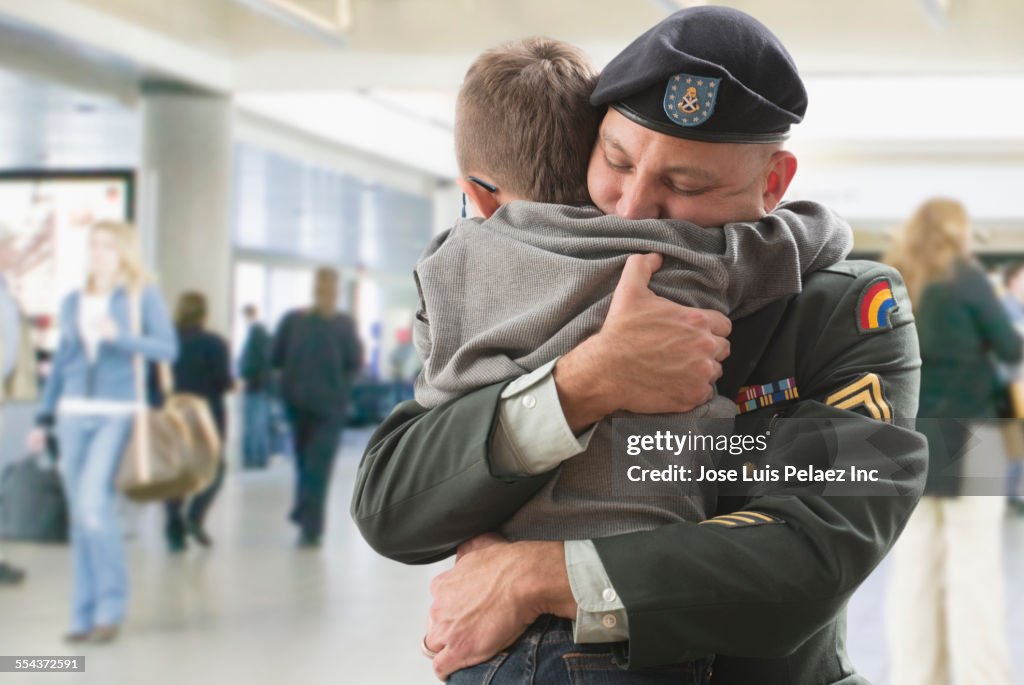Caucasian returning soldier hugging son in airport