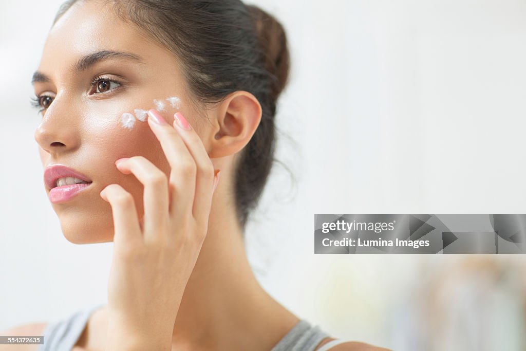 Woman applying moisturizer to cheek