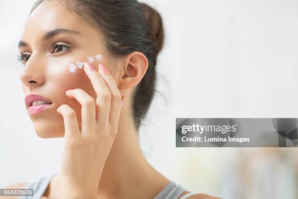 woman applying moisturizer to cheek - face cream stock pictures, royalty-free photos & images