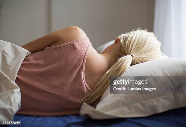 rear view of woman sleeping in bed - woman back pillow blonde stock pictures, royalty-free photos & images