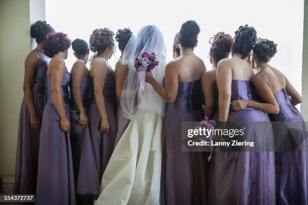 rear view of bride and bridesmaids looking out window - bruidsmeisje stockfoto's en -beelden