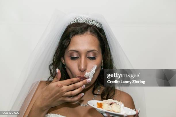 bride with messy face eating wedding cake - hochzeitstorte stock-fotos und bilder