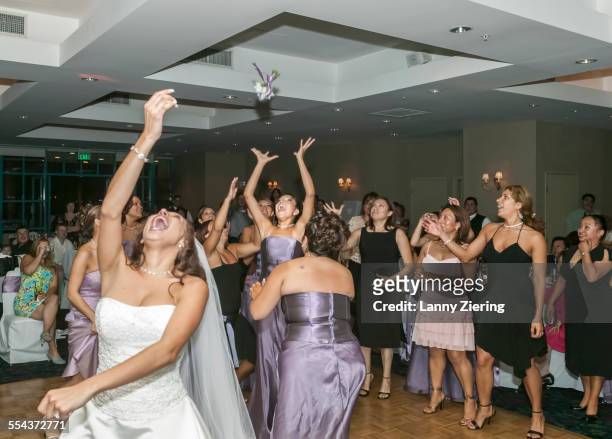 bride tossing bouquet to bridesmaids in wedding reception - ricevimento di nozze foto e immagini stock