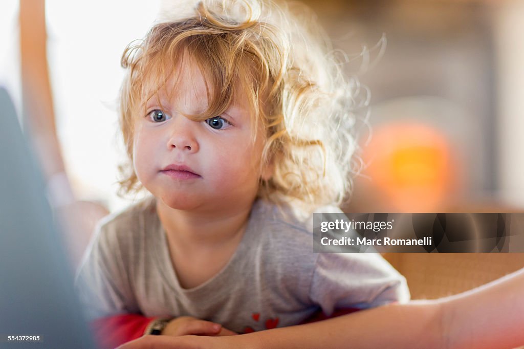 Caucasian baby boy peering at computer screen