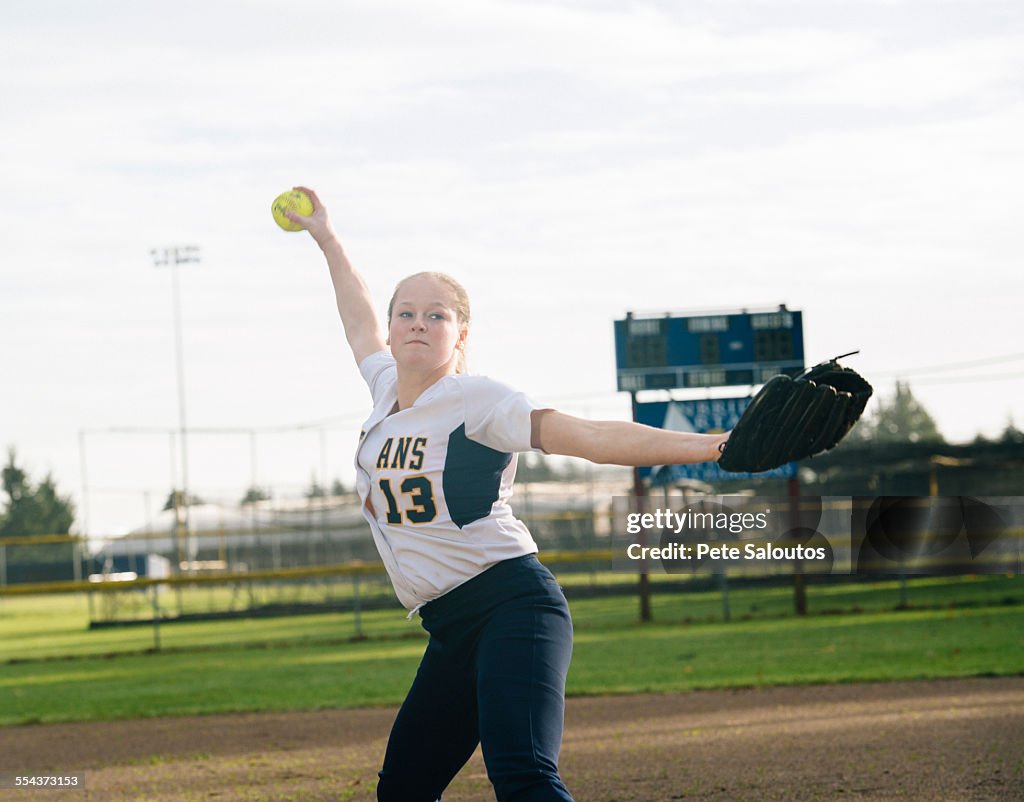 Caucasian softball player pitching ball in field