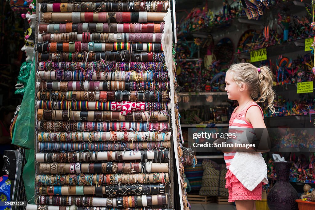 Caucasian girl admiring woven bracelets for sale in market