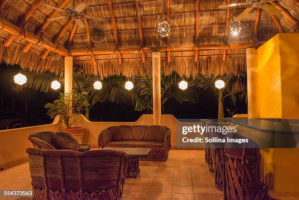 sofas and chairs with bar on outdoor patio at night - hut interior stock pictures, royalty-free photos & images