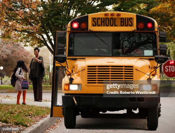 african american woman waiting with daughter for school bus - school bus stock pictures, royalty-free photos & images
