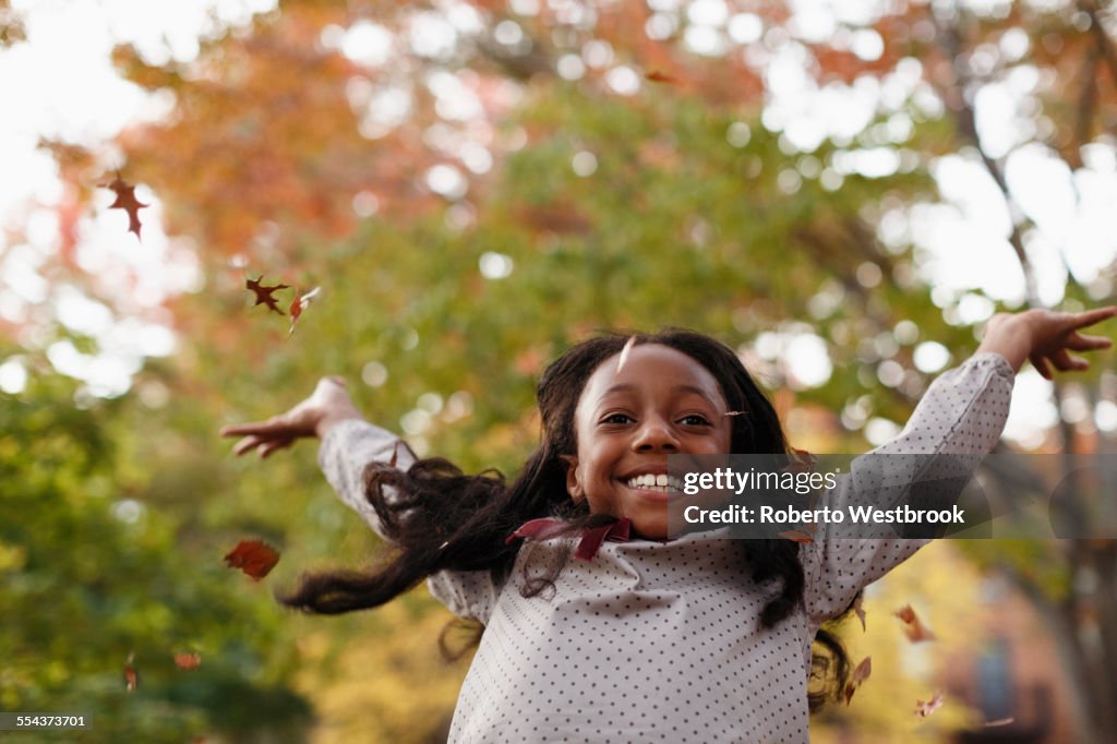 Low angle view of African American girl playing in autumn leaves