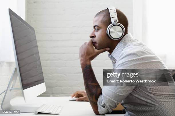 mixed race businessman listening to headphones and working at desk - walkman closeup stock pictures, royalty-free photos & images