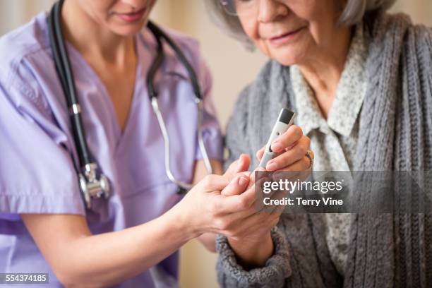 nurse giving blood sugar test to patient in home - diabetes patient stock pictures, royalty-free photos & images