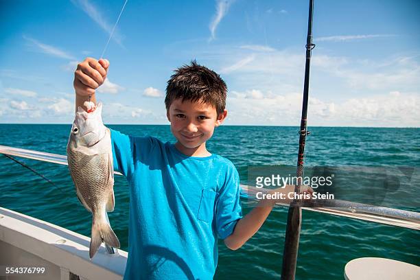 young asian boy holding up the fish he just caught - kids fishing stock pictures, royalty-free photos & images