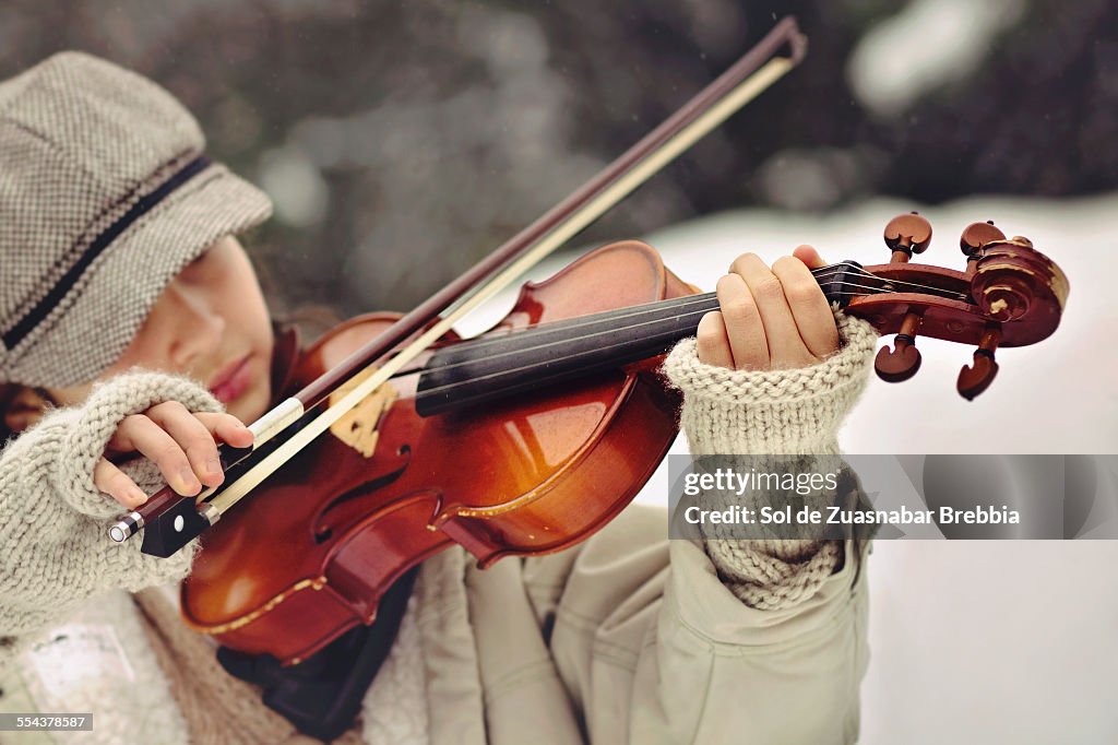 Girl with hat and fingerless gloves playing violin