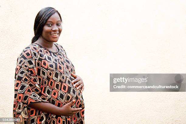 a pregnant woman putting hands on her belly - commerceandculturestock stock pictures, royalty-free photos & images