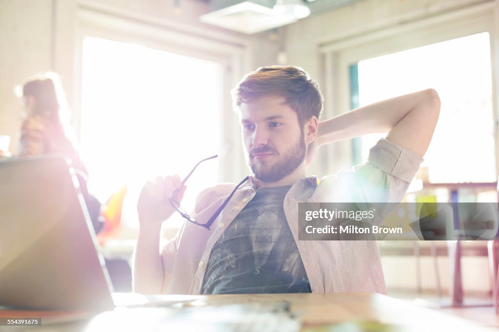 Gelegenheitsunternehmer, der am Laptop im sonnigen Büro arbeitet