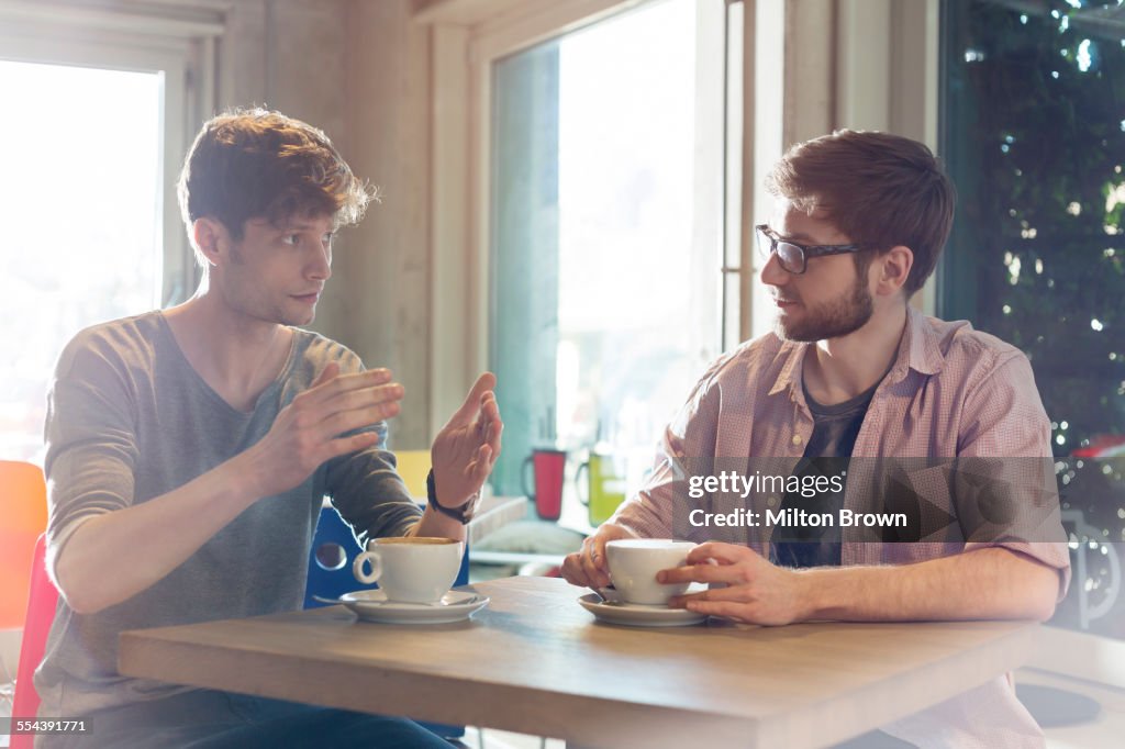 Men talking and drinking coffee in cafe