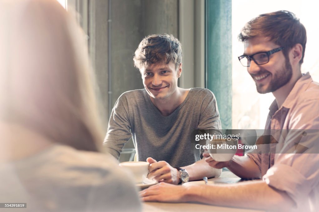 Friends talking and drinking coffee in cafe