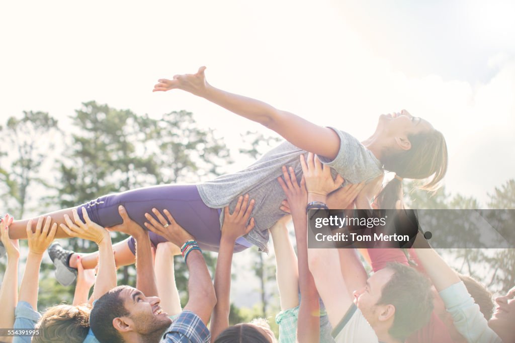 Carefree woman crowdsurfing supported by team