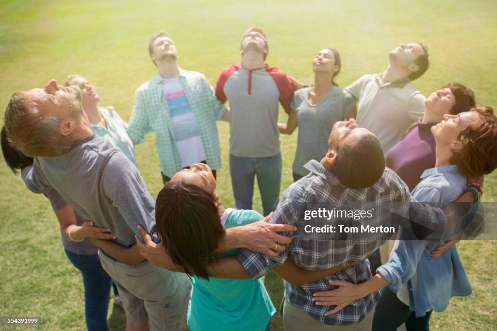 Team forming connected circle basking in sunny field