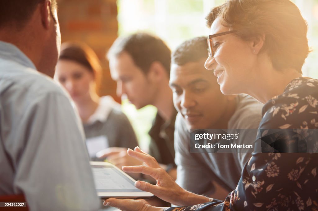 Les gens d’affaires partagent une tablette numérique en réunion