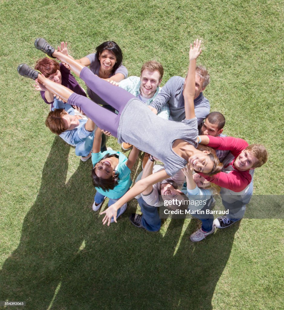 Carefree woman crowdsurfing supported by team