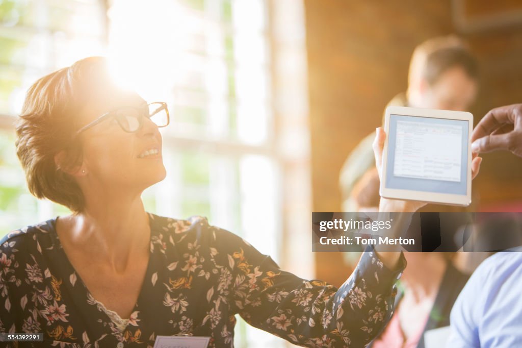 Woman using digital tablet in sunny meeting