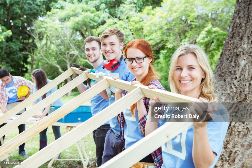 Retrato de voluntarios sonrientes levantando el marco de construcción