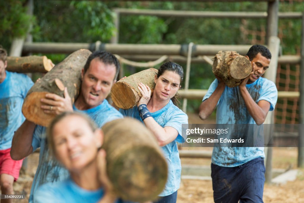 Determined team carrying logs on boot camp race course