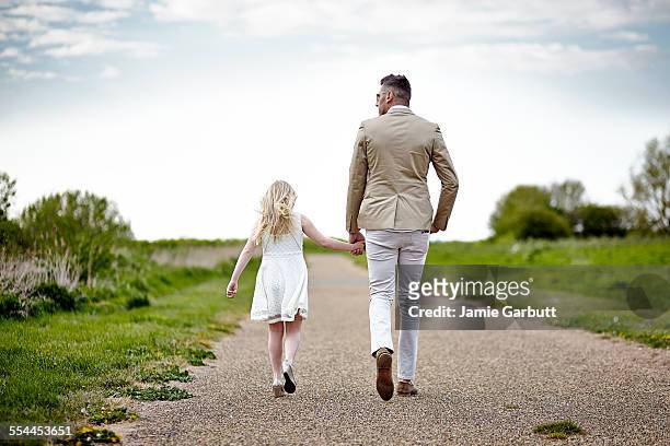 early 30's male with his daughter walking together - leanincollection father stock pictures, royalty-free photos & images