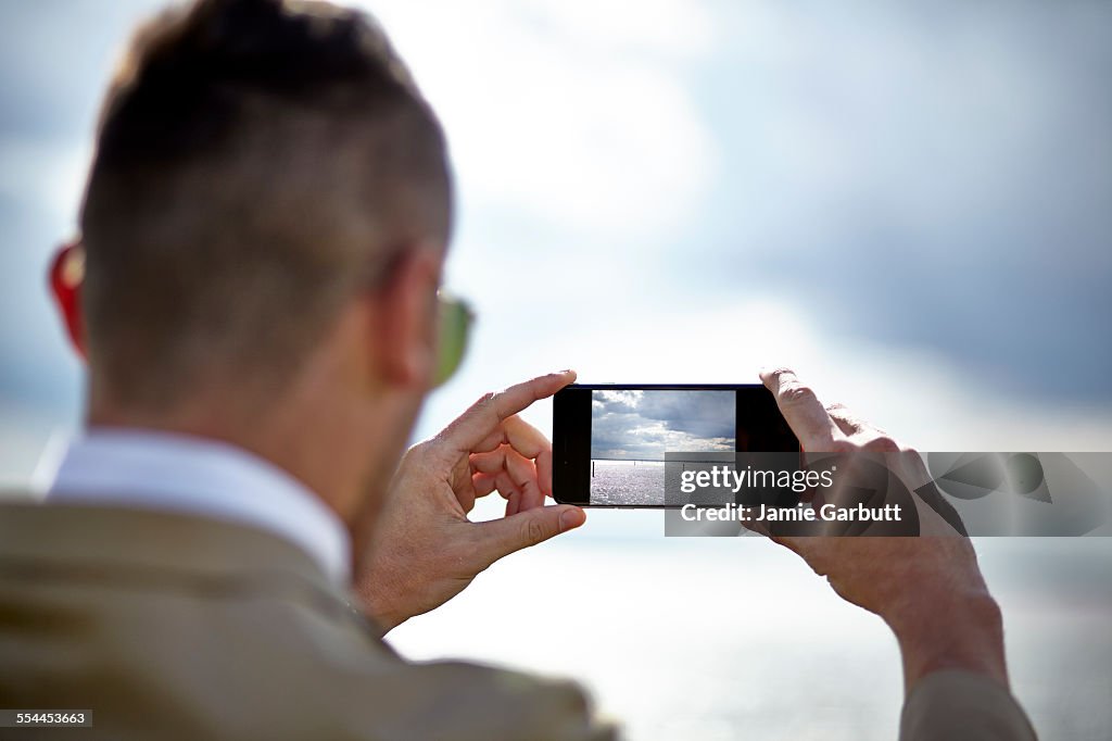 Early 30's male taking a photograph with his phone